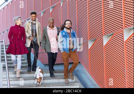 Giovani amici che camminano giù per le scale urbane e moderne Foto Stock