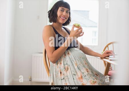 Ritratto donna incinta felice mangiare pane tostato avocado Foto Stock