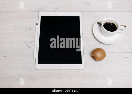 Tavoletta, tazza di caffè e kiwi su superficie di legno Foto Stock