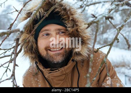 Ritratto di uomo sorridente che indossa giacca con cappuccio in inverno Foto Stock
