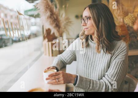 Donna bionda che beve caffè in un bar Foto Stock