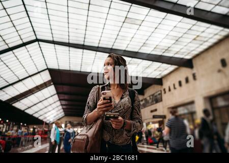 Giovane donna con telefono cellulare all'interno di un edificio in città Foto Stock