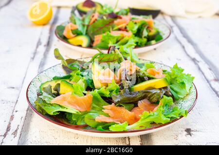 Due piatti di insalata verde pronta con rucola, lattuga Lollo Rosso, spinaci, foglie di barbabietola, avocado, insalata di mais e salmone Foto Stock