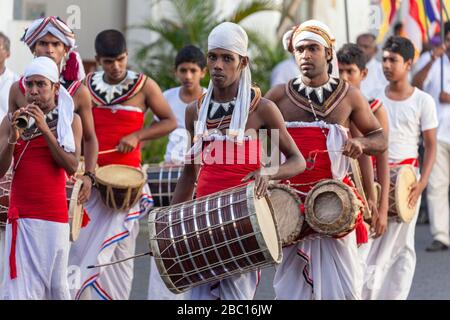 Uomini vestiti con tamburi e corna tradizionali durante un festival buddista a Galle, Sri Lanka Foto Stock