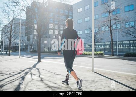 Giovane donna sportiva con protesi delle gambe che cammina in città Foto Stock