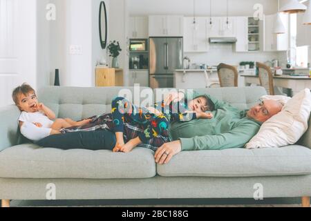 Padre e due bambini si rilassano sul divano Foto Stock