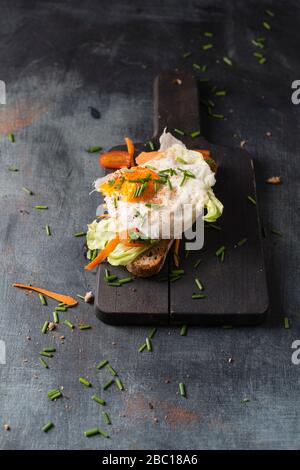 Uovo fritto con pane e verdure sdraiati sul tagliere Foto Stock