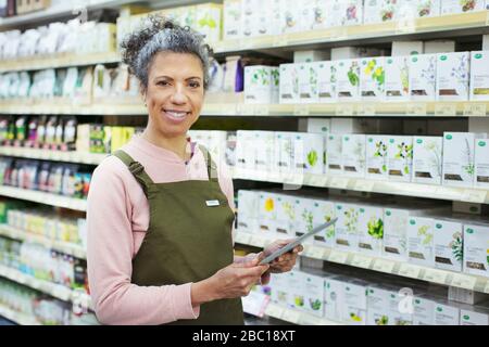 Ritratto femmina sorridente drogheria con tablet digitale che lavora in supermercato Foto Stock