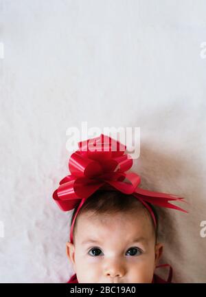 Ritratto di bambina con nastro rosso sulla testa guardando in alto Foto Stock