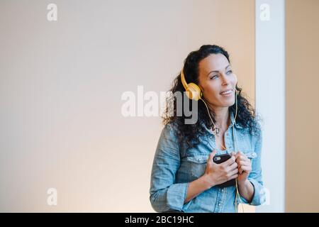 Donna che ascolta musica, indossa le cuffie, usa lo smartphone Foto Stock