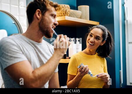 Giovane coppia che sfrega i denti in bagno a casa Foto Stock