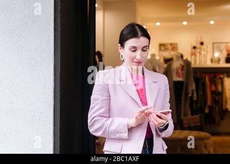 Donna elegante con giacca rosa con smartphone Foto Stock