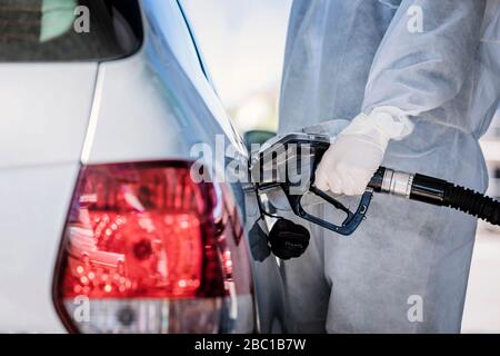 Primo piano di uomo che indossa indumenti protettivi per il rifornimento di auto presso la stazione di servizio Foto Stock