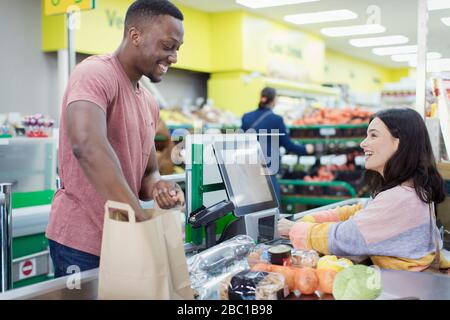 Cassiere che aiuta il cliente alla cassa del supermercato Foto Stock