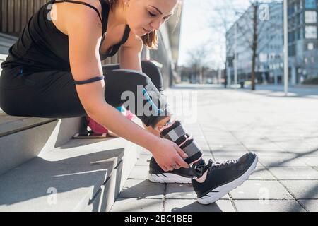 Giovane donna sportiva con protesi delle gambe seduta sulle scale della città Foto Stock