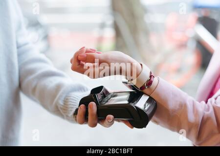 Mano di donna, pagando senza contanti al terminale POS con il suo smartwatch Foto Stock