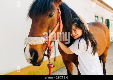 Adolescente con sindrome di Down prendersi cura del cavallo e preparare cavallo a cavalcare Foto Stock