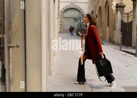 Donna che cammina in un vicolo della città, Firenze, Italia Foto Stock