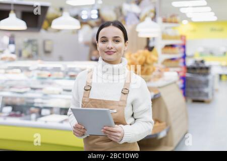 Donna grocer sicuro del ritratto con il tablet digitale che lavora nel supermercato Foto Stock