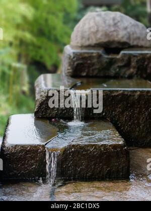 Splendida cascata a tre piani in pietra. Acqua che scorre sulle rocce. Immagine fontana giardino in stile Zen. Focalizzato sul primo piano. Foto Stock