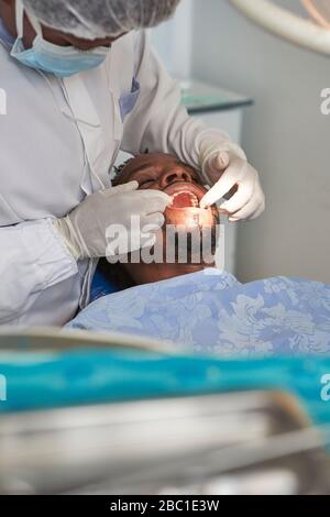 Dentista femmina che esamina i denti di un uomo Foto Stock