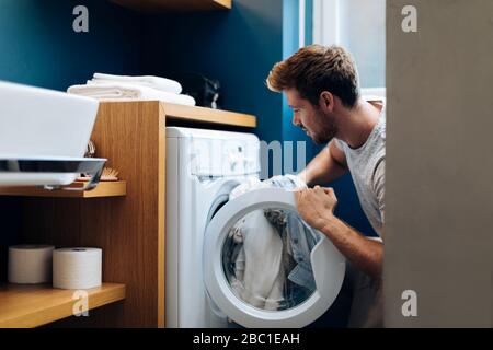 Giovane uomo che fa la lavanderia a casa Foto Stock