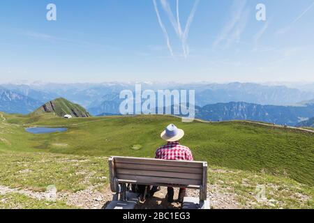 Svizzera, Canton San Gallo, uomo appoggiato su panchina, guardando sulle montagne Foto Stock