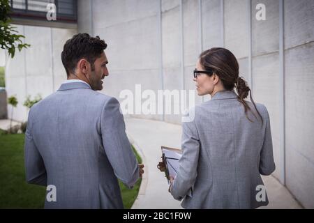 Uomo d'affari e donna d'affari che cammina e parla sul marciapiede Foto Stock