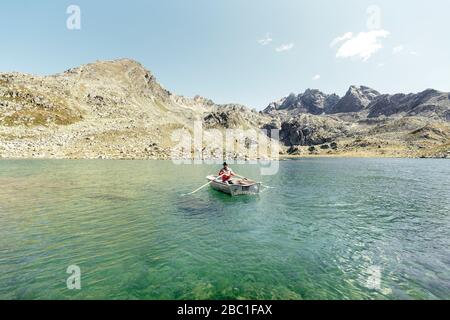 Uomo in barca a remi su una montagna cristallina Lago di Suretta, Graubuenden, Svizzera Foto Stock