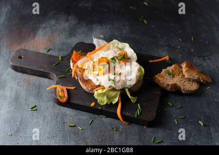 Uovo fritto con pane e verdure sdraiati sul tagliere Foto Stock