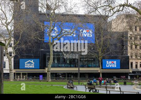 Leicester Square, quasi deserta, nel centro di Londra durante l'epidemia del virus corona. Il cinema Odeon ha segnali che avvertano le persone di salvare vite, ecc. Foto Stock