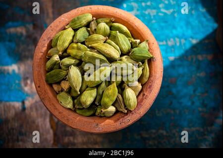 Raccolta di spezie indiane, baccelli di cardamomo verde secchi in vaso di argilla vista dall'alto primo piano Foto Stock