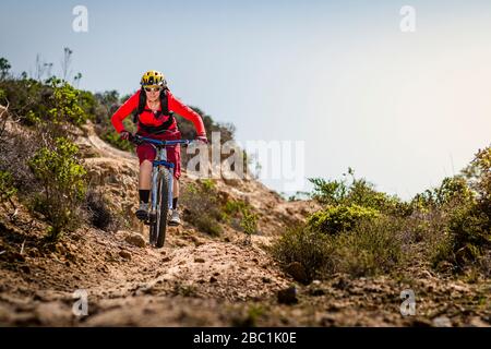 Femmina moutainbiker che scende lungo la pista sterrata, Fort Ord National Monument Park, Monterey, California, Stati Uniti Foto Stock