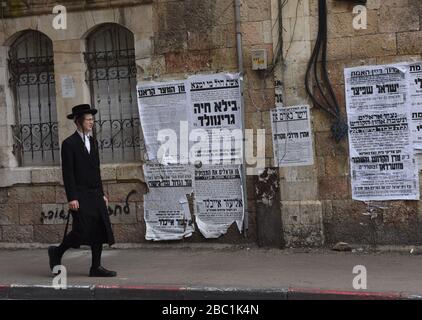 Gerusalemme, Israele. 02nd Apr, 2020. Un ebreo ultra-ortodosso cammina oltre i manifesti che avvertono circa il coronavirus, nel quartiere di Mea Shearim a Gerusalemme, giovedì, aprile. 2, 2020. I casi di coronavirus sono saltati nelle città ultra-ortodosse israeliane, in mezzo alle crescenti preoccupazioni di un grande focolaio di COVID-19 nelle comunità religiose. Foto di Debbie Hill/UPI Credit: UPI/Alamy Live News Foto Stock