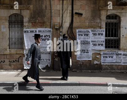 Gerusalemme, Israele. 02nd Apr, 2020. Un ebreo ultra-ortodosso cammina oltre i manifesti che avvertono circa il coronavirus, nel quartiere di Mea Shearim a Gerusalemme, giovedì, aprile. 2, 2020. I casi di coronavirus sono saltati nelle città ultra-ortodosse israeliane, in mezzo alle crescenti preoccupazioni di un grande focolaio di COVID-19 nelle comunità religiose. Foto di Debbie Hill/UPI Credit: UPI/Alamy Live News Foto Stock