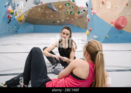 Due donne che hanno una pausa in palestra di arrampicata Foto Stock