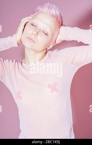 Ritratto di giovane donna con capelli rosa corti con top rosa davanti a fondo rosa Foto Stock