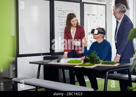 Due uomini d'affari e una donna d'affari che lavorano insieme su un progetto in carica Foto Stock
