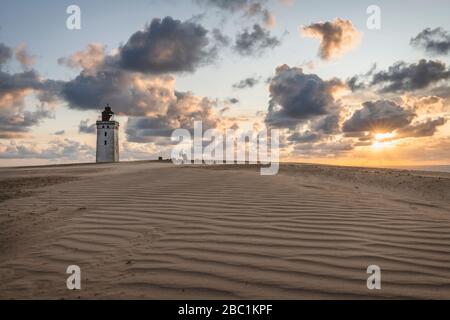 Danimarca, Lonstrup, nuvole su dune di sabbia increspate e Rubjerg Knude Lighthouse al tramonto Foto Stock