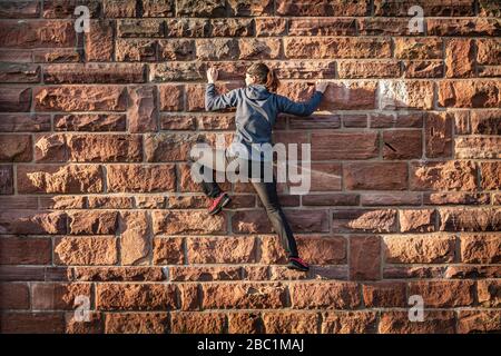 Donna che sale su muro di mattoni di arenaria Foto Stock