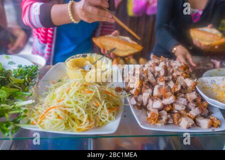 Donna vietnamita fare sandwich di maiale - Banh mi presso venditore ambulante Foto Stock