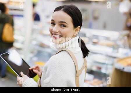 Ritratto sorridente, sicuro femmina drogheria con tablet digitale che lavora in supermercato Foto Stock