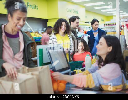 Cassiere che aiuta i clienti al checkout supermercato Foto Stock