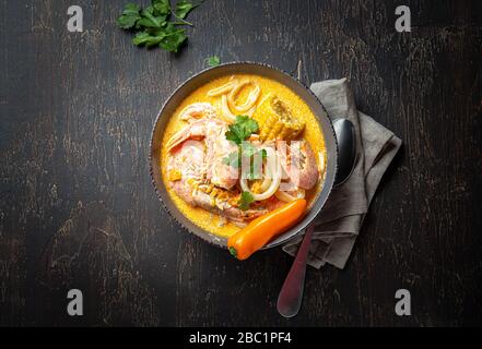 Zuppa peruviana di pesce Chupe de Camarones in ciotola grigia, vista dall'alto. Foto Stock
