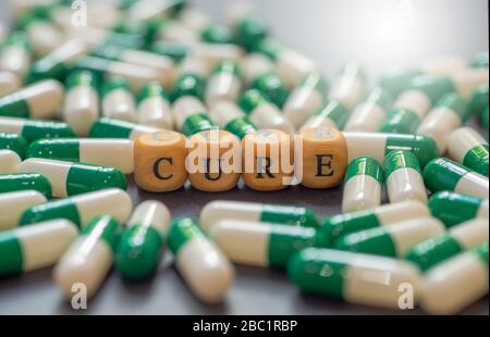 CURA parola su blocco di legno alfabeto con pillole verdi come sfondo. Foto Stock