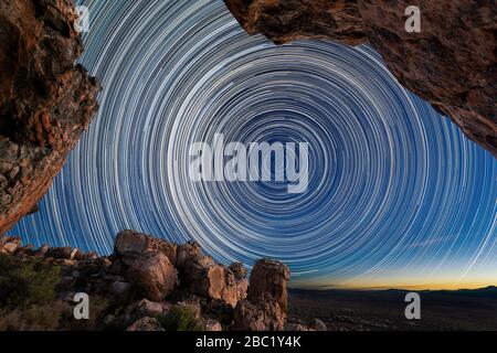 Una splendida fotografia notturna con i sentieri circolari stellari incorniciati da rocce drammatiche in primo piano, prese nelle montagne di Cederberg in Occidente Foto Stock