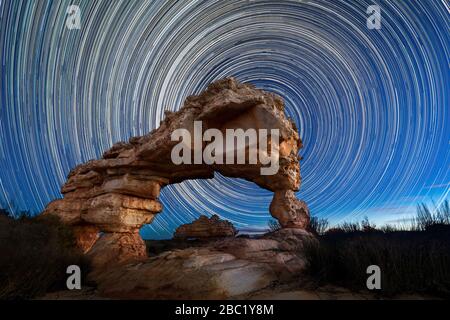 Una splendida fotografia notturna del cielo con percorsi circolari stellari dietro un suggestivo Rock Arch, presa nelle montagne di Cederberg nel Capo Occidentale, Sud AF Foto Stock