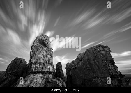 Un paesaggio a lunga esposizione in bianco e nero con maestose formazioni rocciose in primo piano e veloci nuvole in movimento nel cielo, prese nel Cedersb Foto Stock