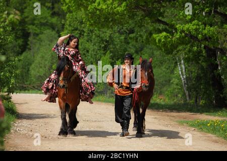 Coppia di zingari in costumi tradizionali passeggiate con un cavallo nei boschi estivi Foto Stock