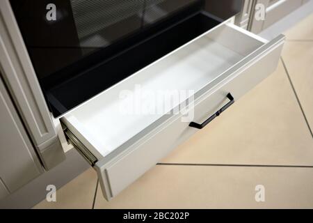 Parte del Contemporary Kitchen Interior - ripiano sotto il forno parzialmente aperto con manopola nera classica Foto Stock